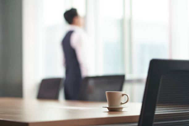 istock cup of coffee on table with business man thinking in background 1296674580