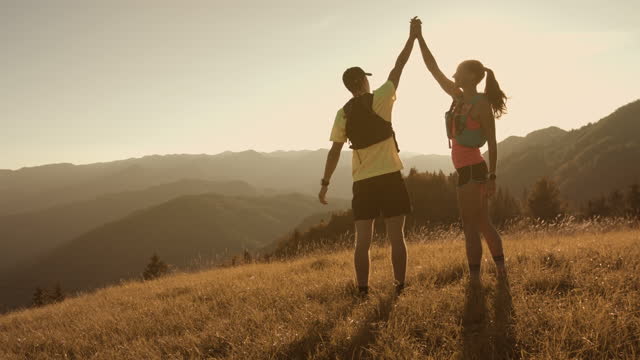Athlete couple running and reaching top of the hill, moutain view - success
