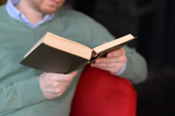 istock A man in a green sweater reading a book 1296676504
