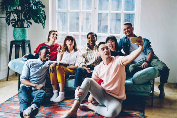 istock Diverse millennial people relaxing on comfortable sofa spending leisure time for making photo via smartphone camera, youthful friends taking selfie photo for sharing media content to website 1296677878