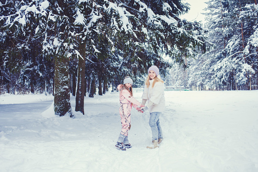 mother and daughter are smiling in the winter snow-covered forest