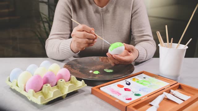 Female hands painting an egg with a brush