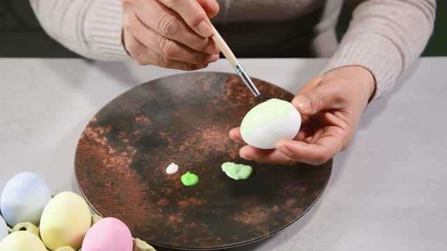 close up of female hands painting an egg with a brush