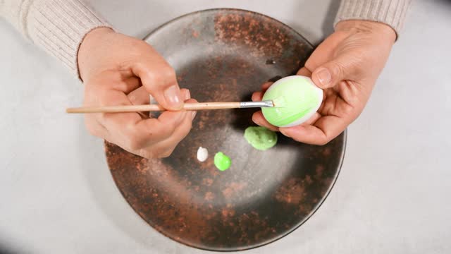 Close up and top view of an egg being painted green