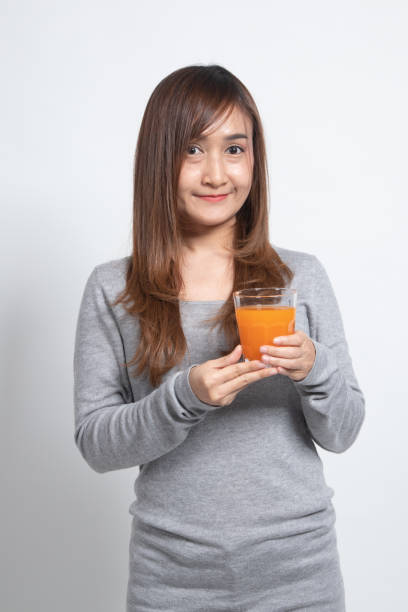 istock Young Asian woman drink orange juice. 1296678849