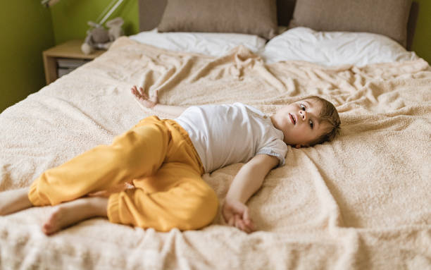 istock Sleepy little boy lying down in bed in bedroom 1296679710