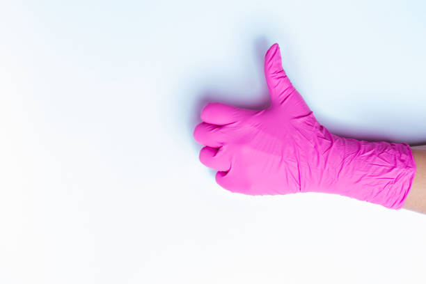 istock Hand in pink medical glove shows class isolated on white background with blank side space. Thumb up. 1296681691