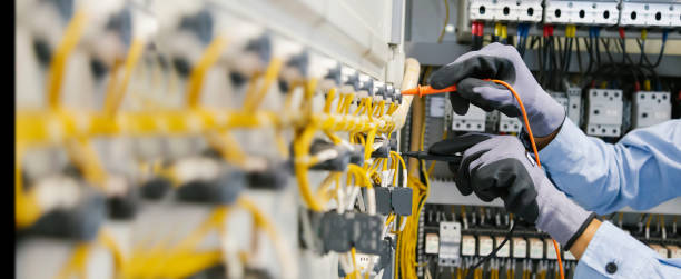 Electrical engineers test electrical installations and wiring on protective relays, measuring them with a multimeter.