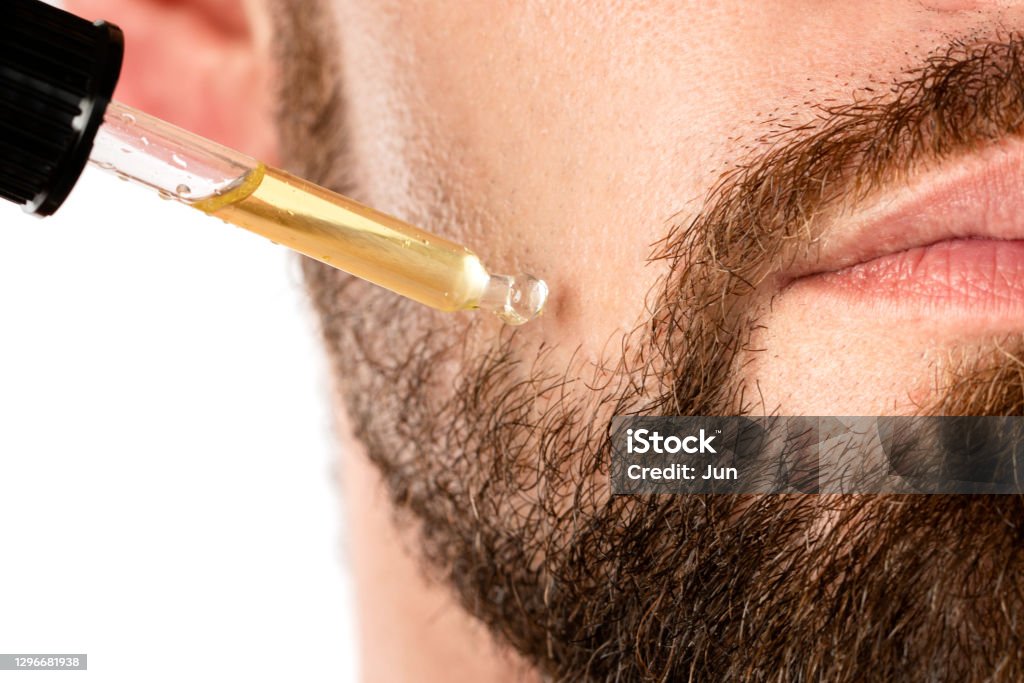 Male face and pipette with a oil for a beard growth Closeup of male face and pipette with a oil for a beard growth Beard Stock Photo