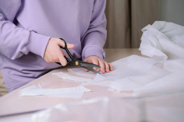 istock Closeup  of female tailor cuting out paper sewing patterns in her workshop 1296682036
