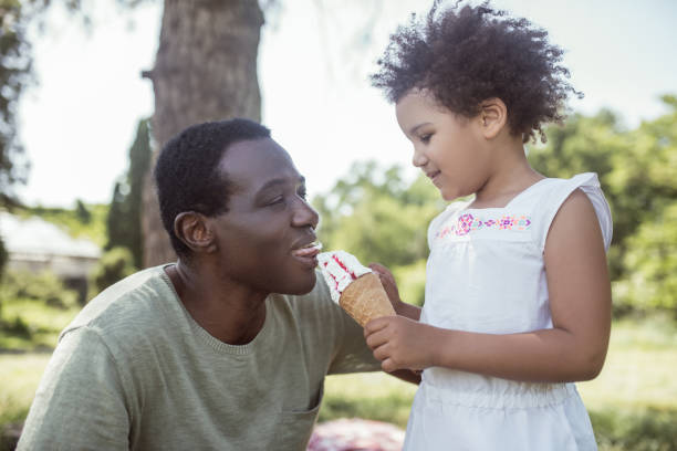 istock Curly-haired cute kid eating ice-cream and spending time with dad 1296686352