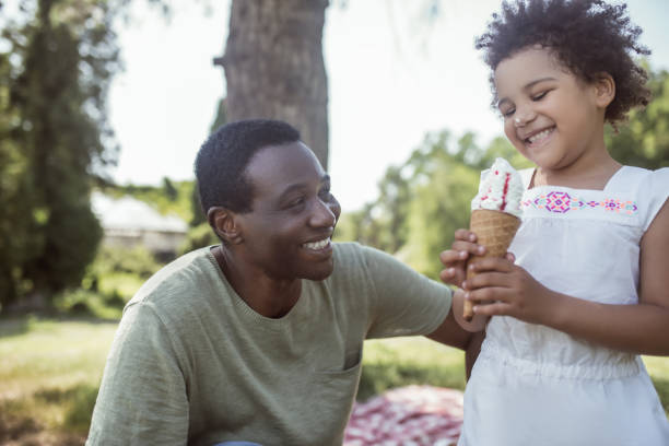 istock Curly-haired cute kid eating ice-cream and spending time with dad 1296686353