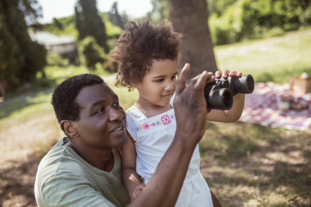 istock Dark-skinned cute girl holding a binocular and looking interested 1296686372