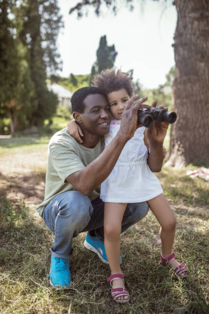 istock Dark-skinned cute girl holding a binocular and looking interested 1296686378