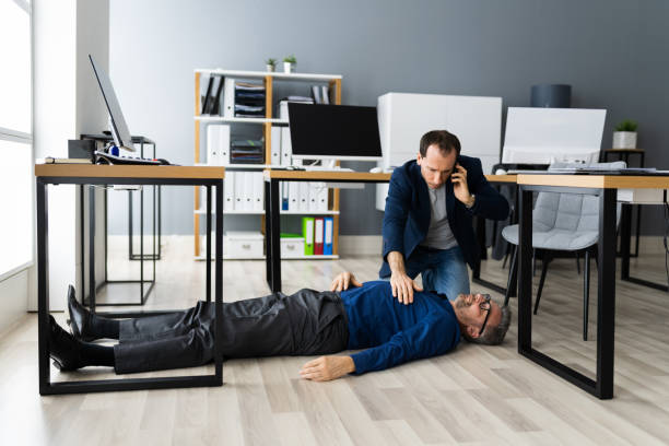 istock Helping Aged Fainted Man On Office Floor 1296686805