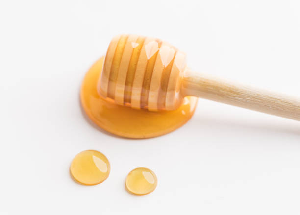 istock Honey dripping off a wooden honey dipper. 1296687619