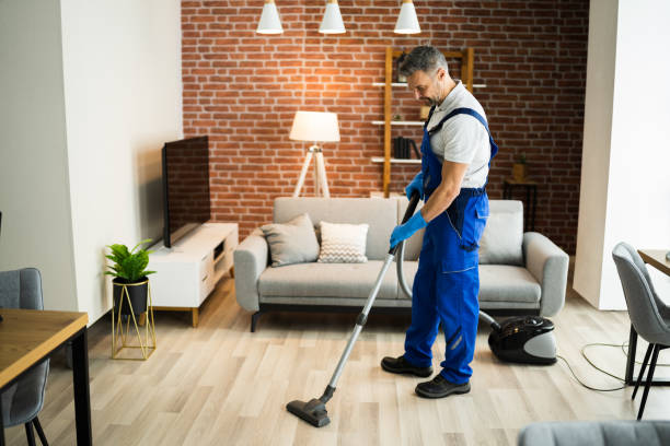 istock Man In Uniform Vacuuming House Floor 1296687993