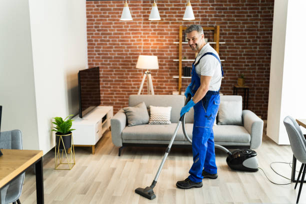 istock Man In Uniform Vacuuming House Floor 1296687997