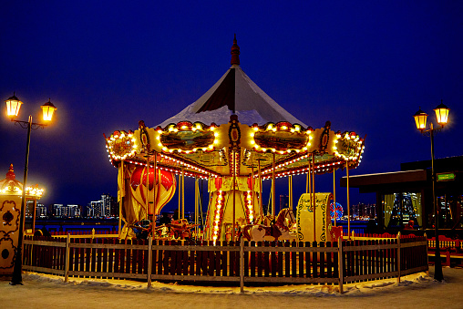 the carousel is illuminated by lights and lanterns. evening cityscape