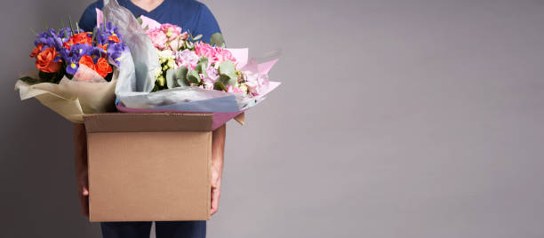 istock White male courier holding a large cardboard box with several bouquets 1296689971