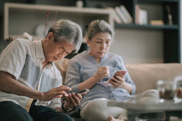 asian chinese senior couple with presbyopia having difficulty  trying to learn using smart phone at living room during weekend leisure time