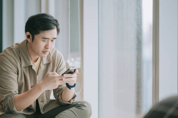 istock asian chinese man sitting on sofa living room using smart phone surf the net 1296690215