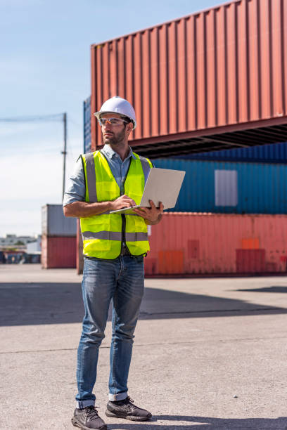 istock Logistics engineer stand on and Pointing up around Shipping container stacker in commercial transport port 1296691787