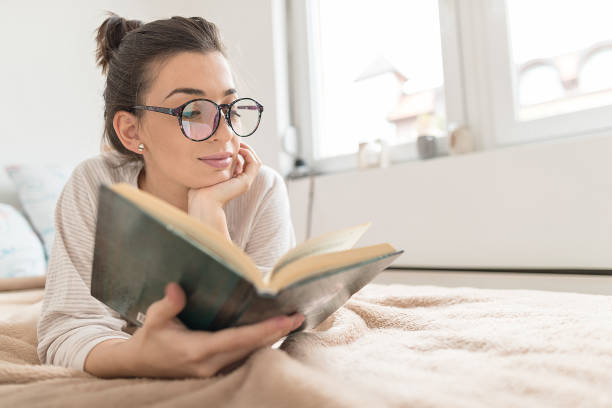 istock Woman reading book in bed 1296695134