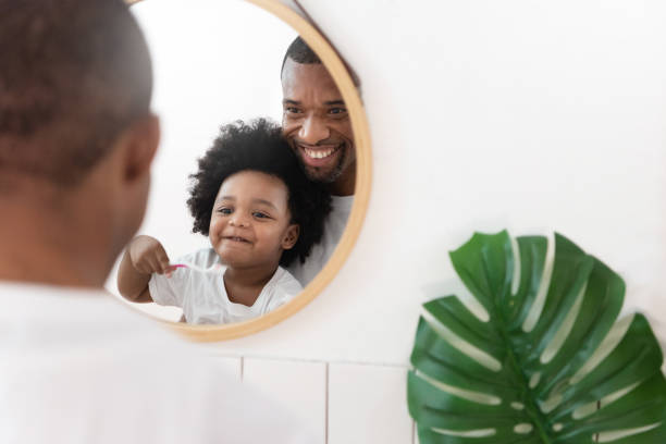 istock African American Father and Son looking at mirror brushing teeth in bathroom. 1296696740