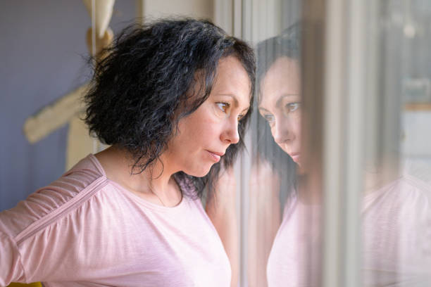 istock Thoughtful woman standing at a window 1296700619