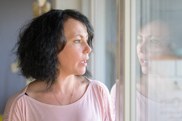istock Thoughtful woman standing at a window 1296700649