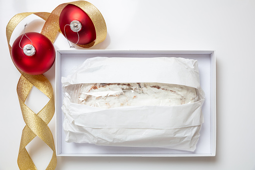 Christmas stollen cake Christstollen isolated on white. Sweet german traditional bread wraped with paper  in a carton box and seasonal decoration. Xmas gift from Dresden