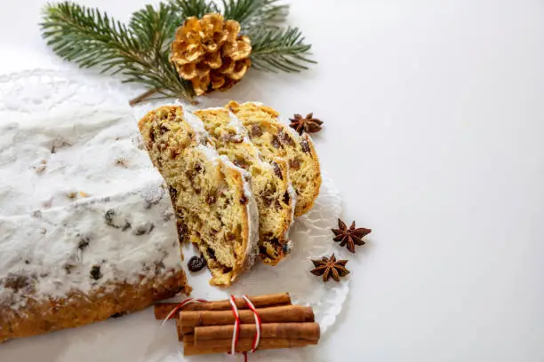 Christstollen slices on white background. Christmas stollen cake sweet german traditional bread, Seasonal dessert with raisins, nuts, spices, dried fruits and icing sugar