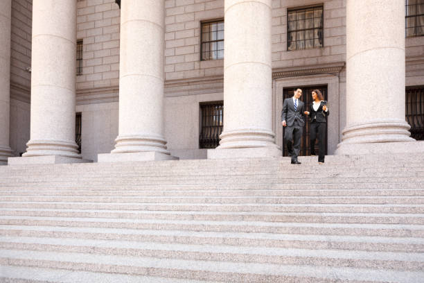 lawyer and client descend courthouse staircase - lawyer young adult suit expressing positivity imagens e fotografias de stock