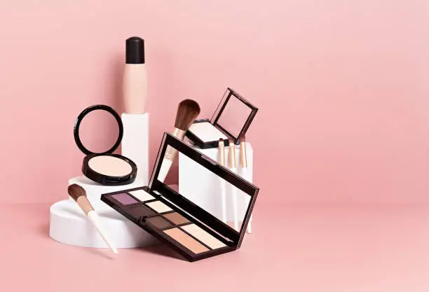 Photo of Make up products prsented on white podiums on pink pastel background.