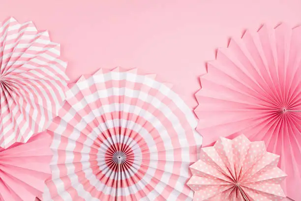 Photo of Festive party background with pink paper circle fans over pastel background. Festival, birthday, baby shower decoration