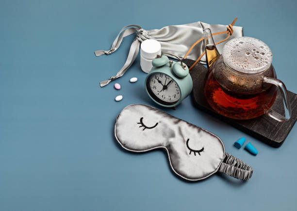 istock Classic alarm clock, sleeping mask, tea pot on blue pastel background.  Minimal concept of rest, quality of sleep, good night, insomnia, relaxation 1296705564