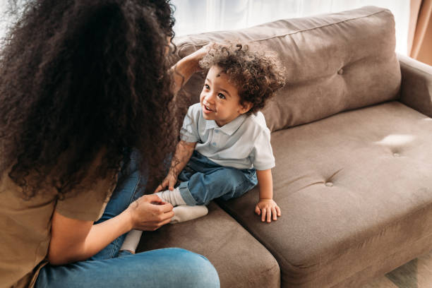 istock Little boy looking at her mother while sitting on a sofa. Young woman and her son spending time together in a living room 1296706059