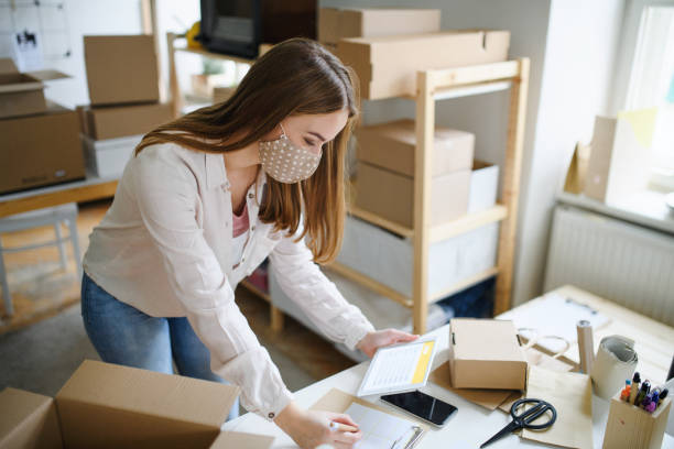 istock Young woman dropshipper with tablet working at home, coronavirus concept. 1296708598