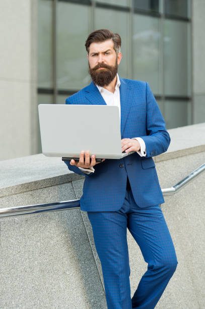 freelance worker in formal fashion suit work online using laptop computer device modern technology urban outdoors, freelancing - surfing wireless vertical outdoors lifestyles imagens e fotografias de stock
