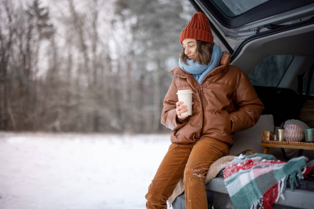 istock Woman with hot tea sitting in car trunk 1296712087