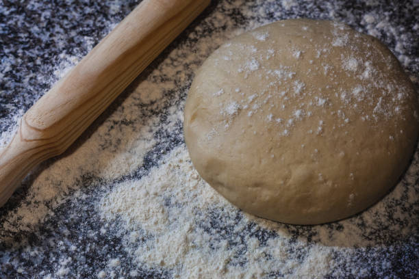 istock Fresh dough on a board with some flour and rolling pin. 1296714435
