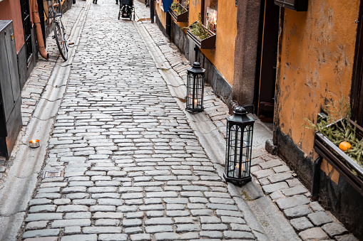 Lanterns stand in front of the entrance to a cafe on a narrow street in Gamla Stan, Stockholm, Sweden.
