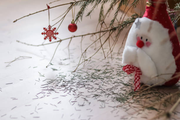 istock Santa claus soft toy under the Christmas tree with needles crumbling. 1296714973