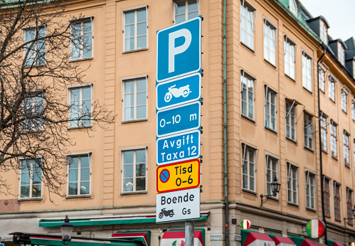 STOCKHOLM, SWEDEN - JANUARY, 2020: Swedish car parking road sign with parking rules in the background of city streets and buildings