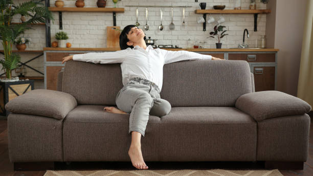 istock Relaxed woman stretches sitting on comfortable grey sofa 1296716170