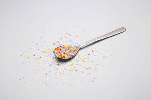 Spoon with microplastics Spoon with colored microplastics on grey background microplastic stock pictures, royalty-free photos & images