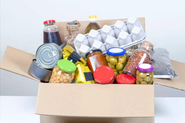 istock Food donations box with grocery products on white table 1296718594