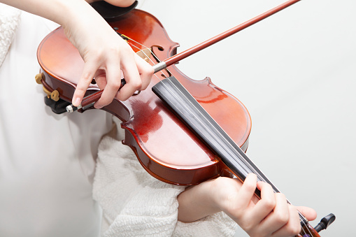 Girl practicing playing violin at home. Close up of hand.