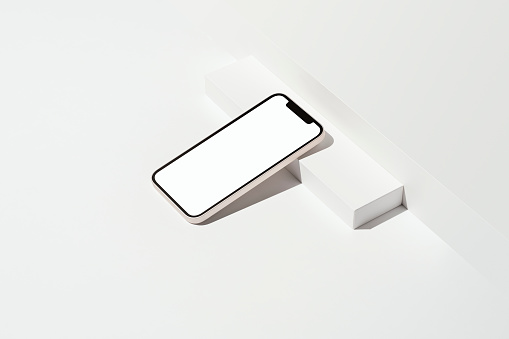 Blank white screen smart phone mockup, template with clipping path on white background. Phone leaning against to white box.